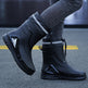 Black rubber boots with white stripes worn by a person on a blurred street background