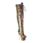 A single over-the-knee boot covered in iridescent gold sequins, featuring a high stiletto heel, platform sole, and black lace-up front, shown against a plain white background.