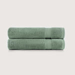 Two folded sage green towels stacked horizontally on a light gray background.