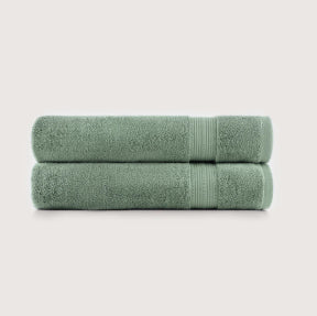 Two folded sage green towels stacked horizontally on a light gray background.