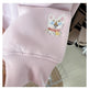 Pink sweater with embroidered cat design on a chair.
