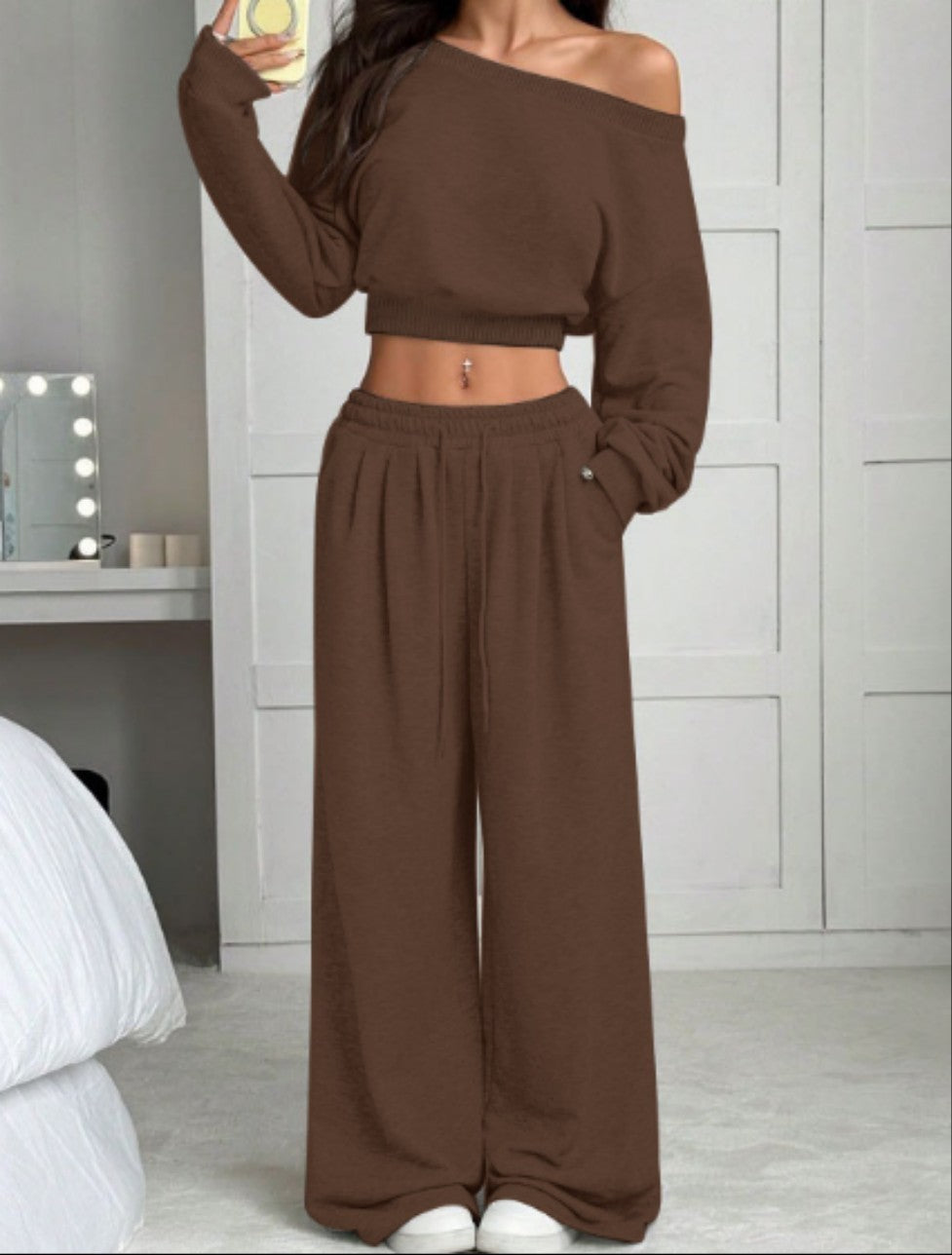 Person wearing a brown off-shoulder top and wide-leg pants in a bedroom setting.