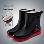 Black rain boots with red soles on a gray background