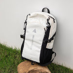 White and black backpack on a rock with a grassy background