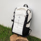 White and black backpack on a rock with a grassy background