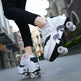 Person wearing white roller skates with black soles on a city street.