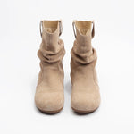 Par de botas de tobillo beige sobre un fondo blanco