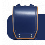 A navy blue leather school backpack with tan leather trim and silver metal rivets, shown from a front-facing perspective on a stylized white background.