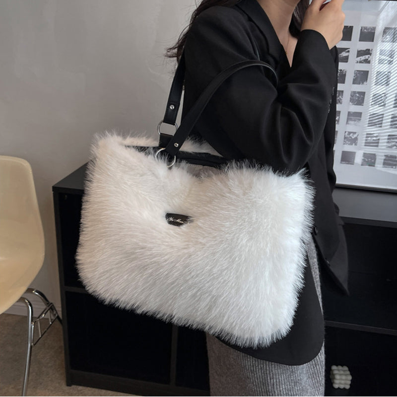 Person holding a white fluffy handbag indoors.