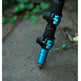 Close-up of a fishing rod section with black and bright blue anodized aluminum joints, standing on concrete outdoors with blurred green foliage in the background.