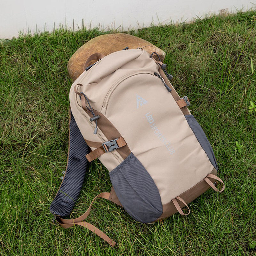 Beige and brown backpack on grass with a bear in the background