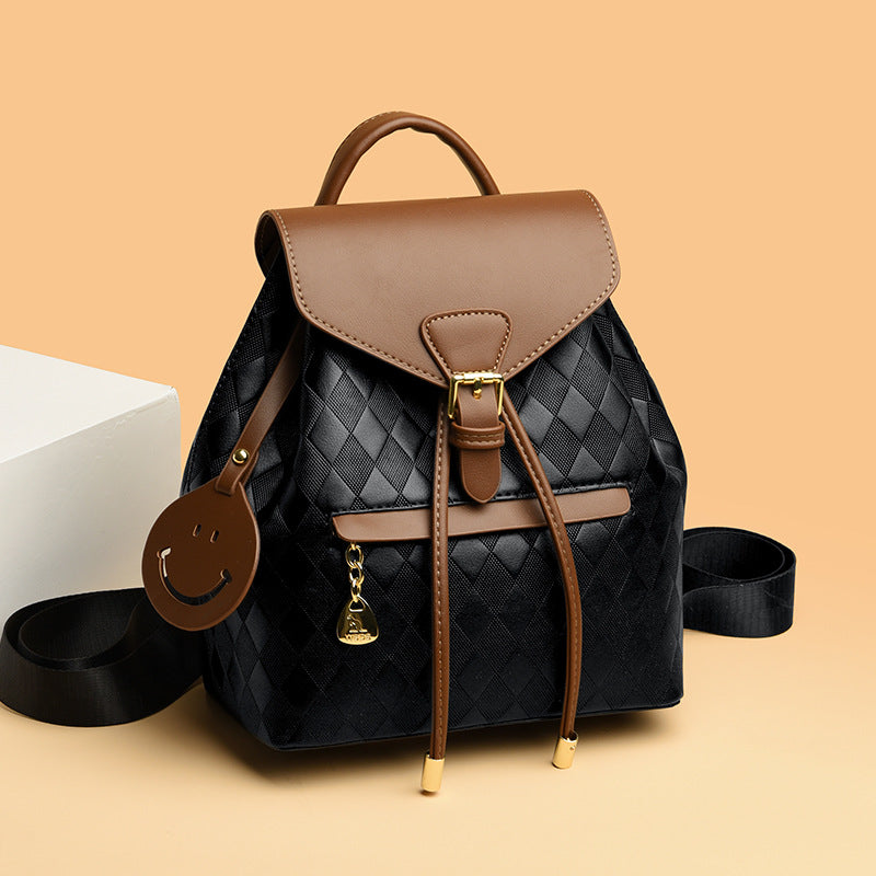 Black quilted backpack with brown leather accents on a beige background