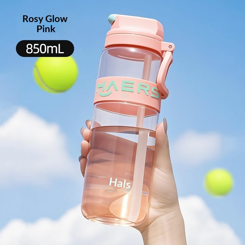 Hand holding a pink Hals water bottle with tennis balls in the background