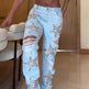 Person wearing light blue jeans with star-shaped embellishments in a room.