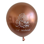 A metallic rose gold foil balloon with white Arabic calligraphy and the text 'Eid Mubarak' printed on it, shown against a plain white background.