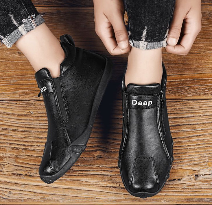 Black ankle boots with 'Daap' branding on a wooden floor.