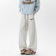 Person wearing light gray sweatpants with plaid cuffs and a blue sweater with text on a white background