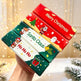 Four Christmas-themed rectangular boxes stacked diagonally, held by a hand. The boxes feature festive holiday illustrations and text including 'Merry Christmas', 'Santa Claus', 'Ho Ho Ho', and a green Christmas gift icon.