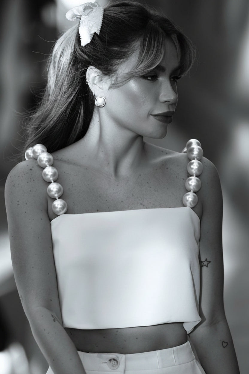 Black and white photo of a woman wearing a strapless dress with pearl straps.