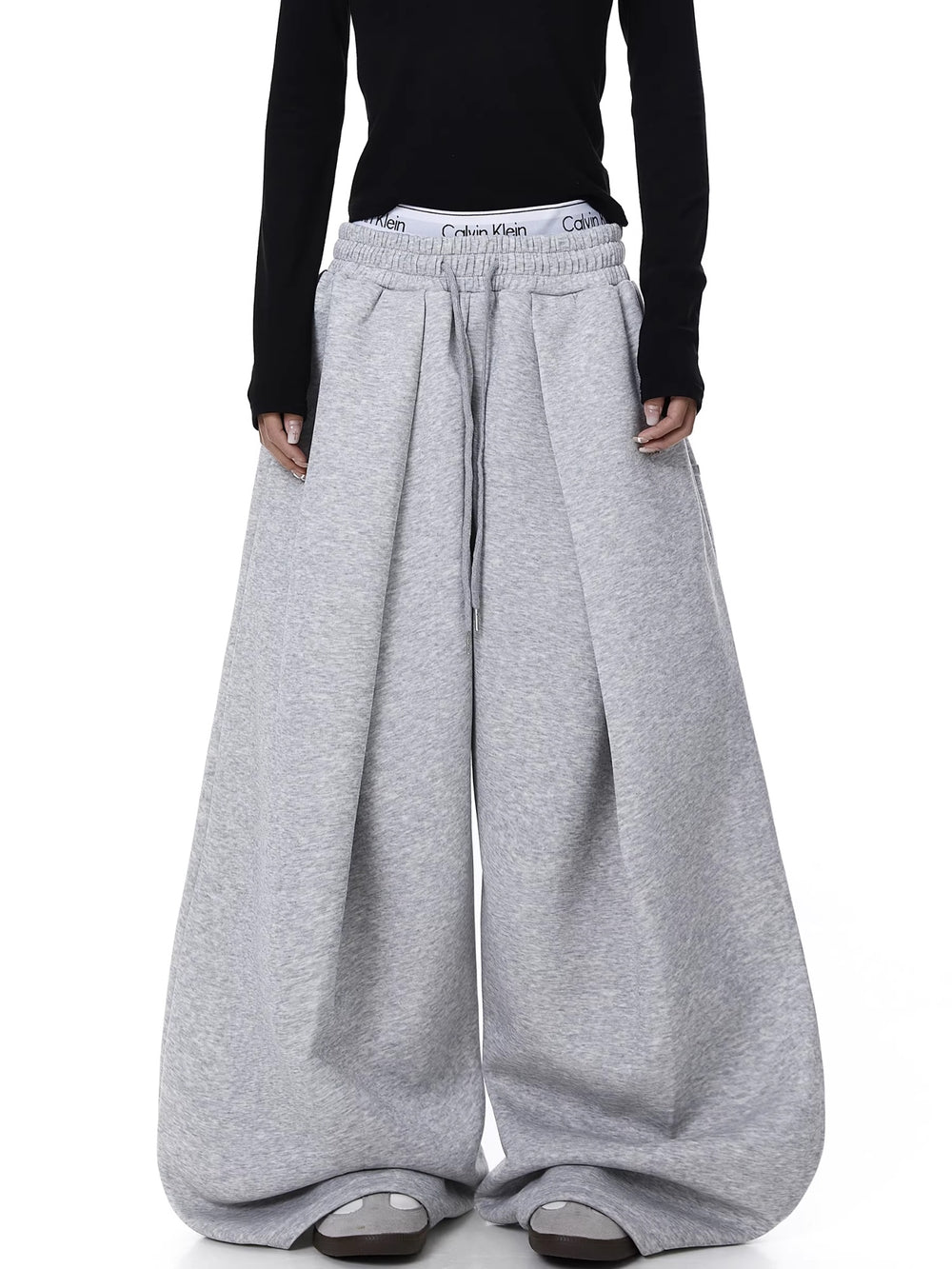 Person wearing gray wide-leg pants with a black top on a white background