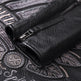 Close-up of black leather glove with zipper on an embroidered background