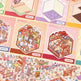 Colorful 3D paper model kit with cartoon characters and buildings on a pink background