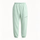 A pair of light mint green sweatpants with an elastic waistband and ankle cuffs, featuring a zippered pocket on the left thigh, shown against a plain white background.
