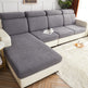 Gray sectional sofa in a living room setting with a white rug and wooden floor.