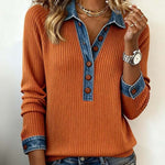 Person wearing an orange sweater with denim collar and cuffs on a plain background
