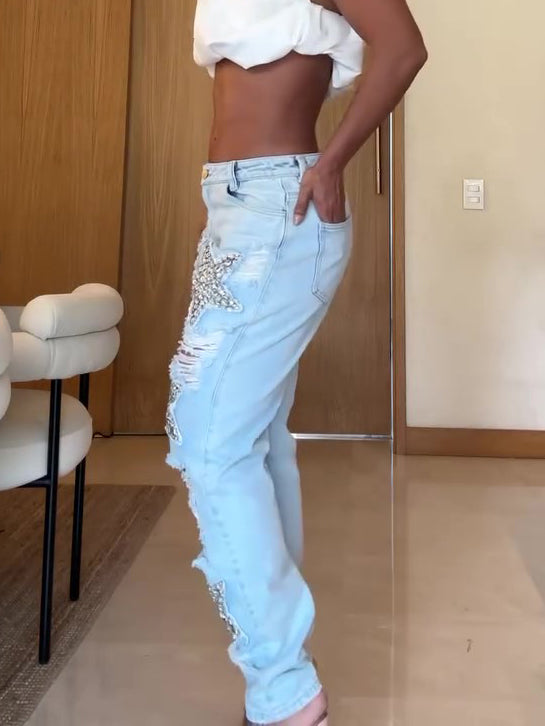 Person wearing light blue distressed jeans and a white top in an indoor setting.