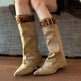 Beige knee-high boots with leopard print cuffs worn by a person sitting on a couch.